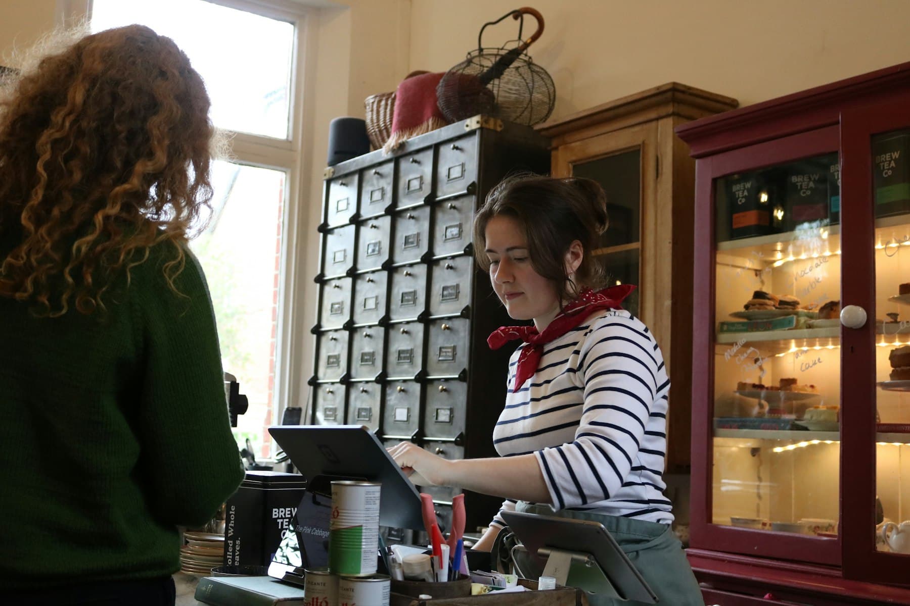 A shop employee helping a customer using a tablet at the counter