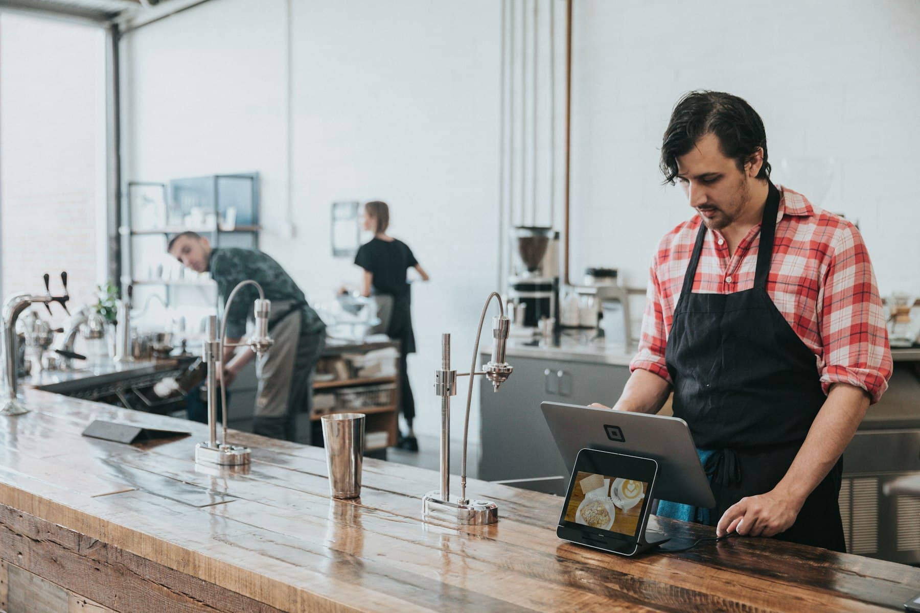 A small business owner checking a tablet behind the counter